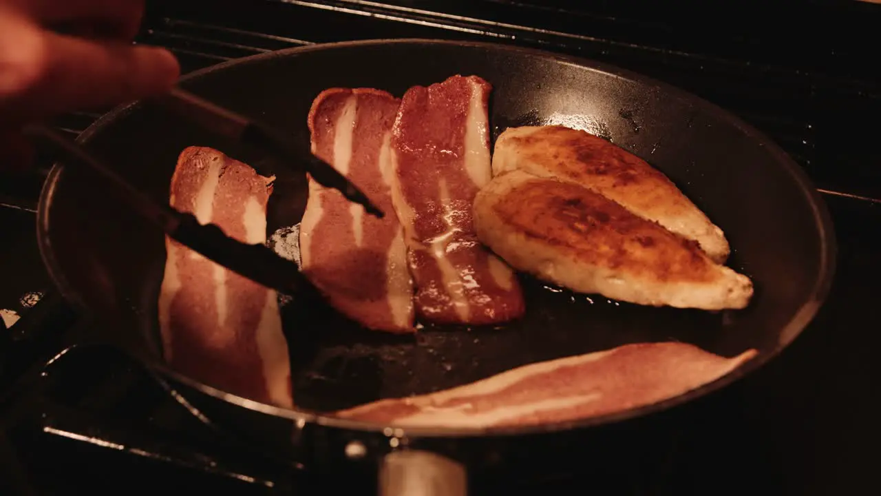 Chef Tongs Turning Over Vegan Bacon in Hot Frying Pan