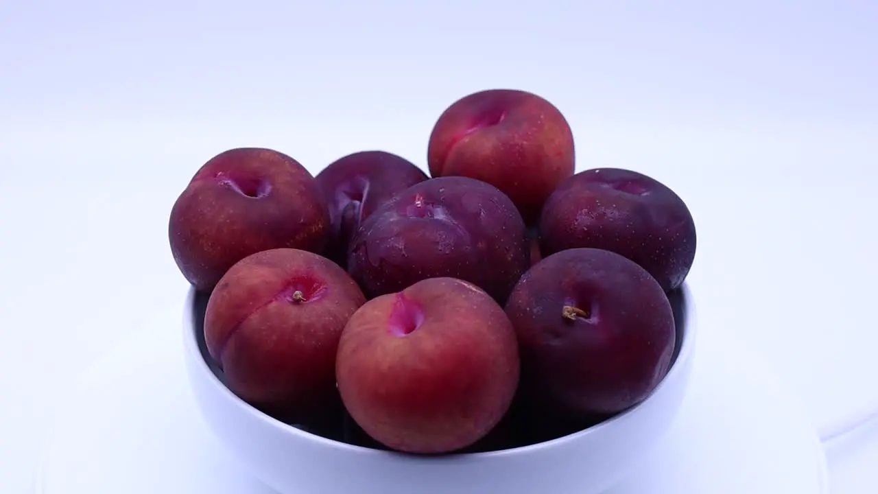 Fresh plums in a bowl isolated on white background