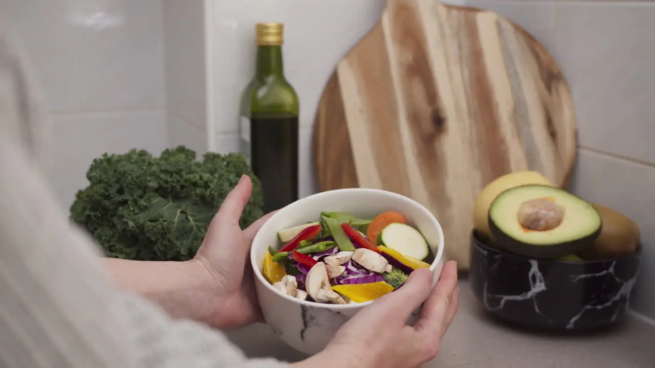 Female hands cooking fresh vegetarian salad and showing the salad bowl with colorful vegetables Weight loss diet and healthy raw meal