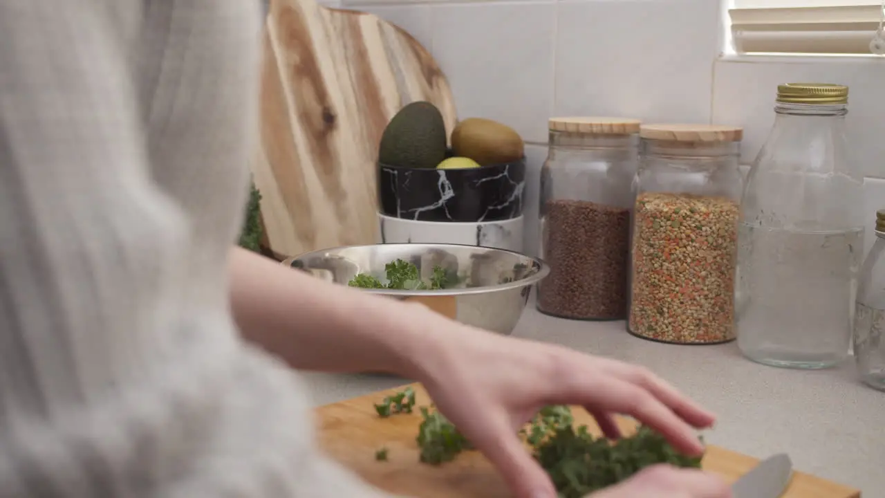 Hands putting greens into salad bowl after chopping Healthy vegan food and weight loss diet