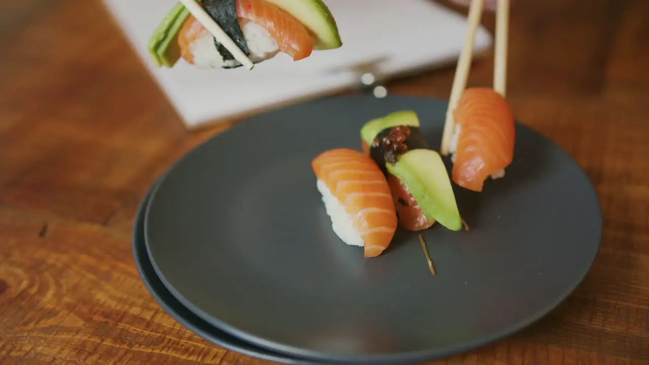 Eating the Japanese way with Sushi Salmon and avocado using chopsticks only