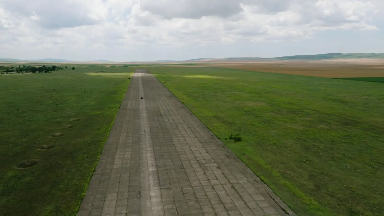 Car driving on wide paved asphalt runway of Shiraki military airfield