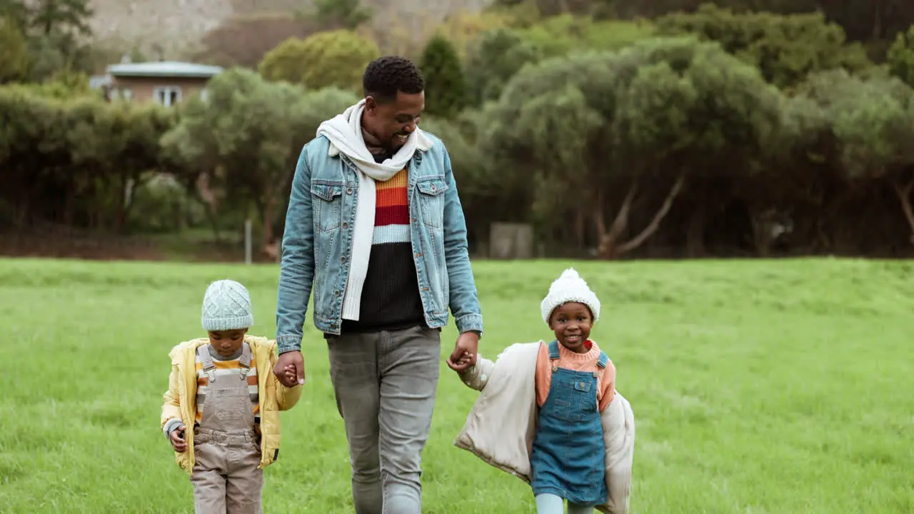 Dad walking and children holding hands in park