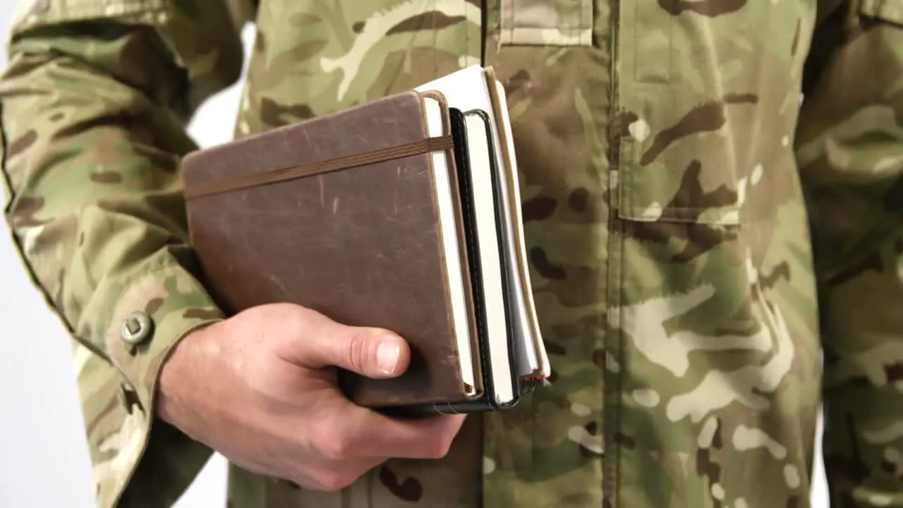 Mid section of soldier holding dairy on white background