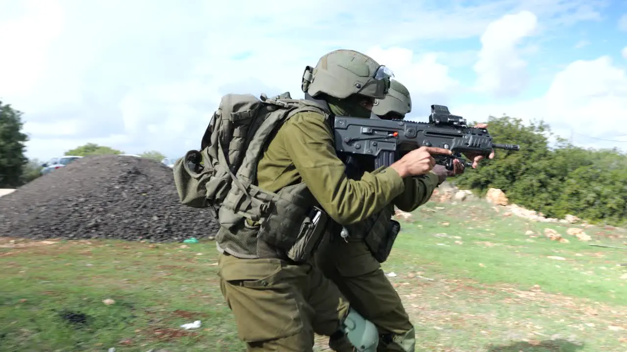 Two Israeli Infantry Army Soldiers Practice Warking in Team Military Tactics Aiming Machine Guns At Training Ground Outdoors