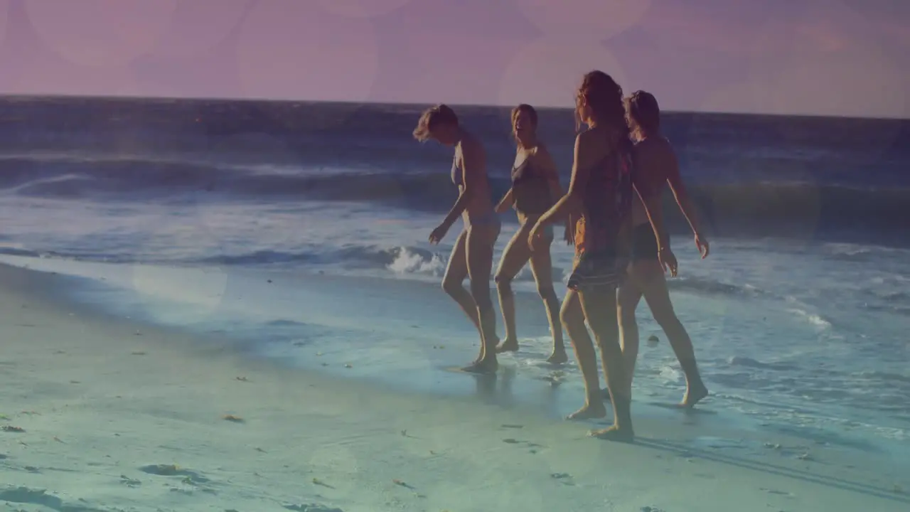 Animation of glowing lights over group of diverse female friends by the sea