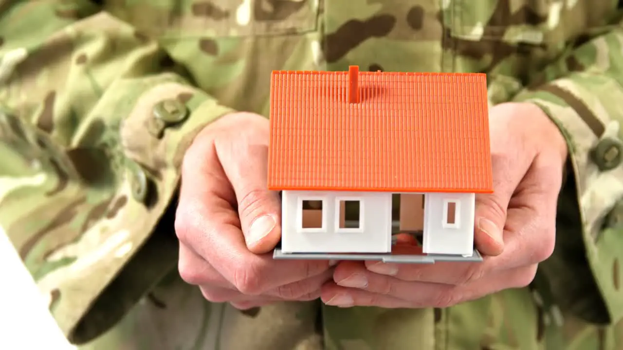 Mid section of soldier holding house model on white background