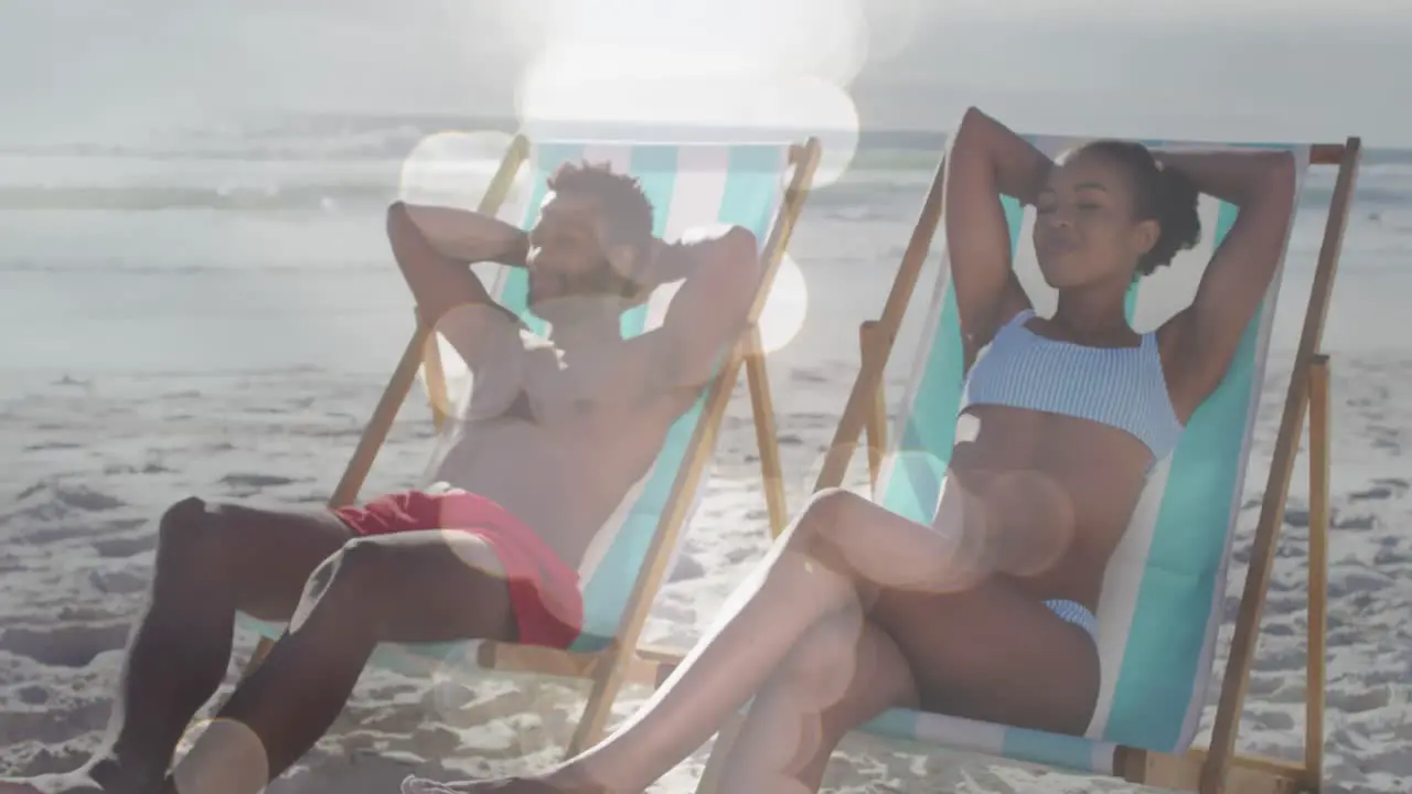 Animation of dots over happy african american couple lying on sunbeds on beach