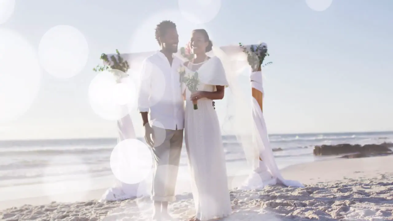 Animation of dots over happy african american newly married couple on beach