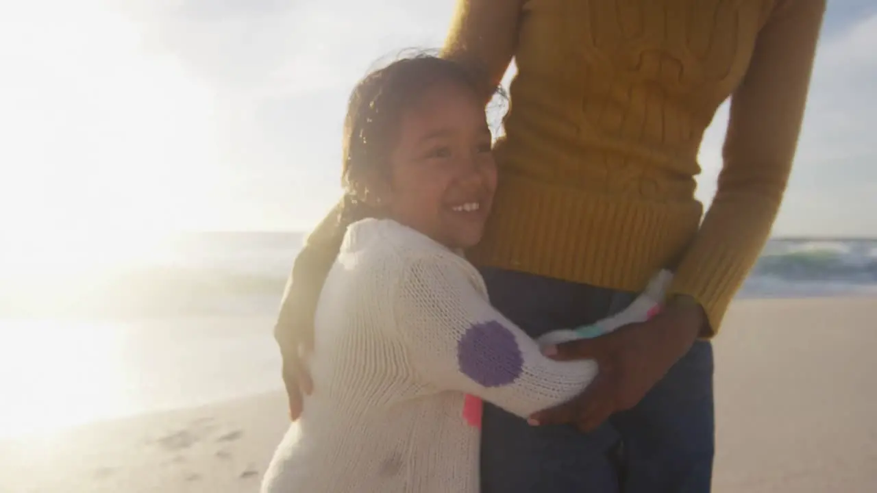 Happy hispanic daughter embracing mother on beach at sunset