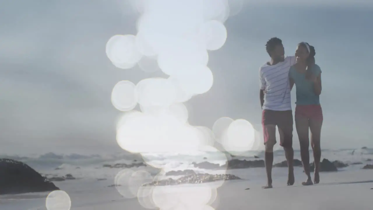 Animation of dots over happy african american couple walking on beach