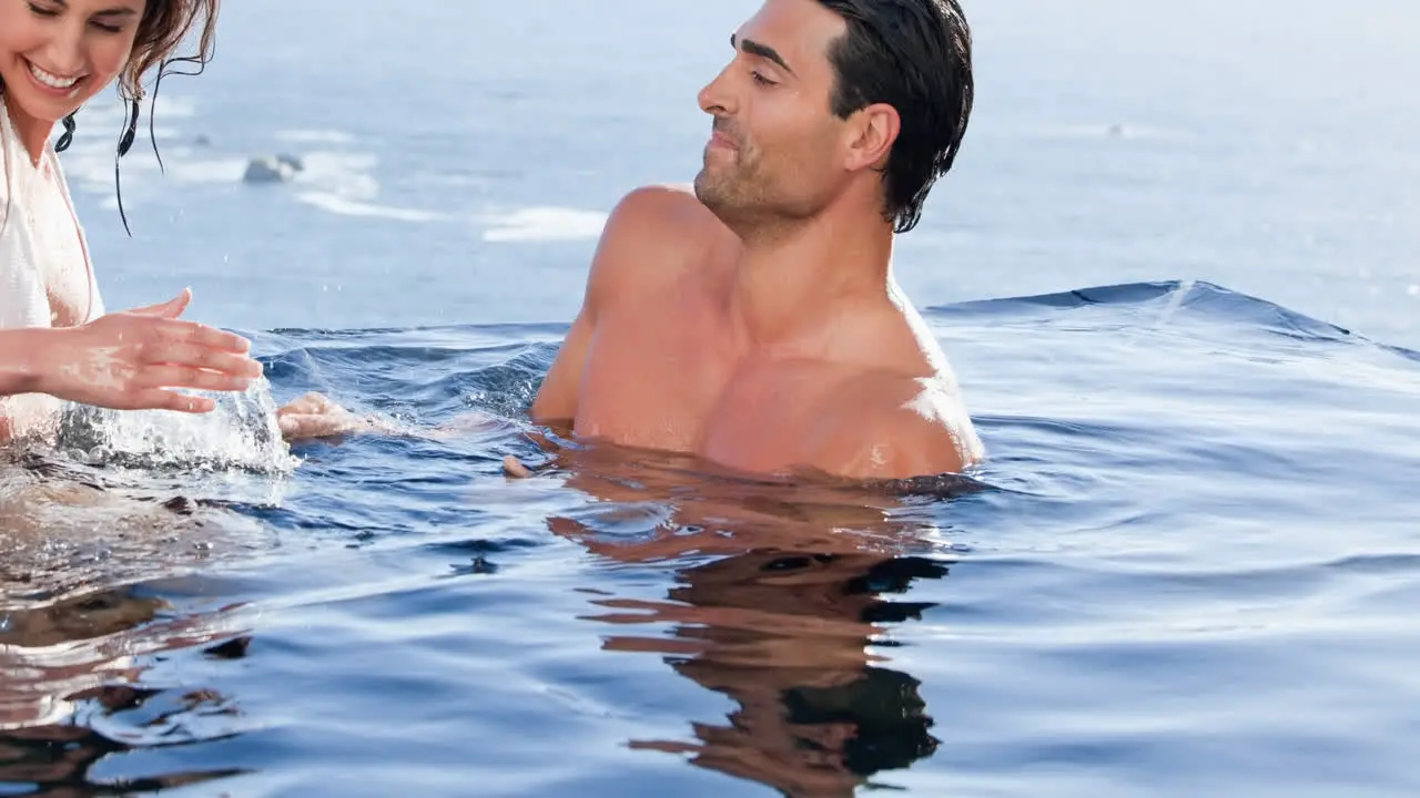 Smiling caucasian couple on holiday splashing in sea