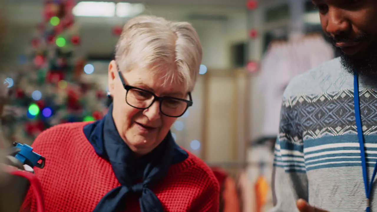 Retail assistant in festive decorated clothing store helping elderly couple during their Christmas frenzy shopping spree Employee offering advice to senior customers during winter holiday season