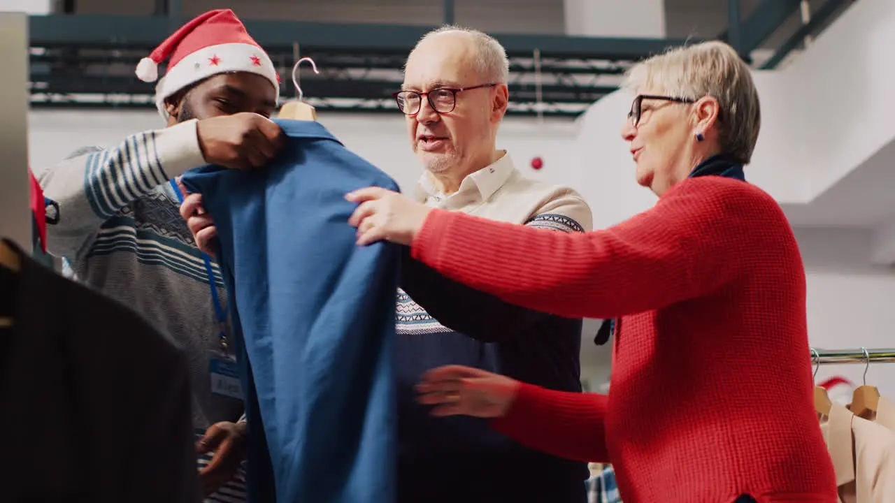 Retail assistant in xmas adorn fashion boutique helping old couple during their Christmas frenzy shopping spree Worker offering advice to aged clients during festive holiday season