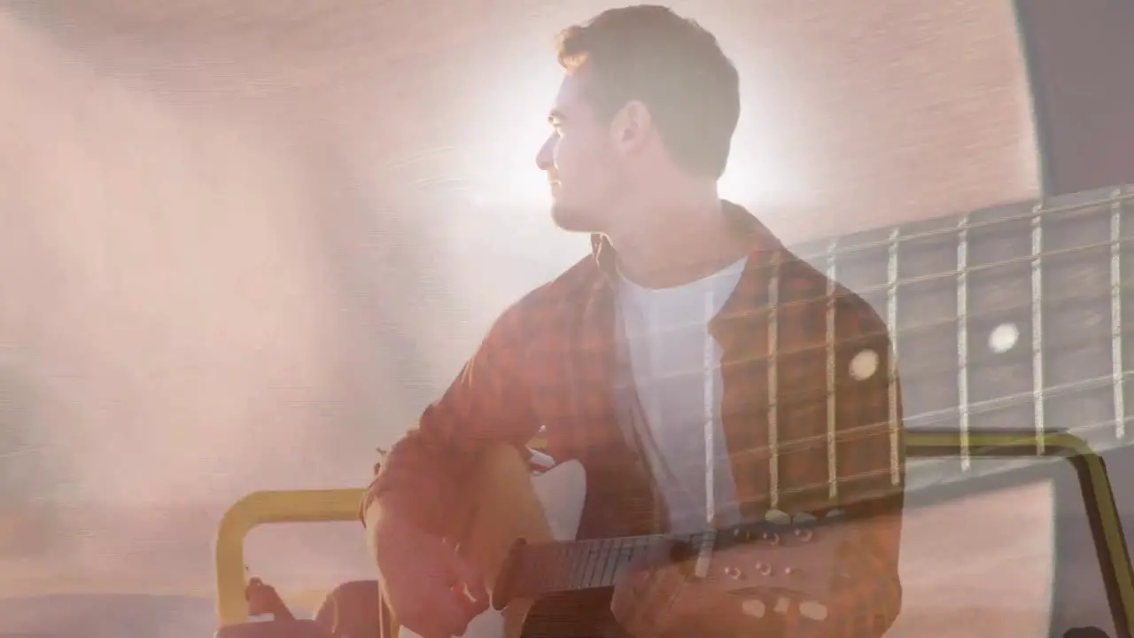 Animation of lights over happy caucasian man playing guitar on beach