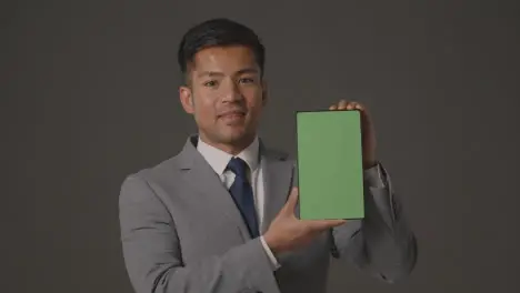 Studio Shot Of Smiling Businessman In Suit Holding Green Screen Digital Tablet