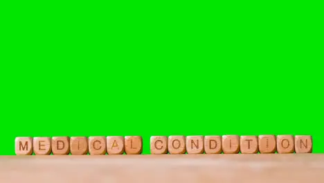 Medical Concept With Wooden Letter Cubes Or Dice Spelling Medical Condition Against Green Screen Background