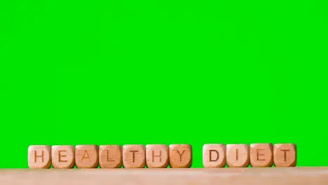 Medical Concept With Wooden Letter Cubes Or Dice Spelling Healthy Diet Against Green Screen Background