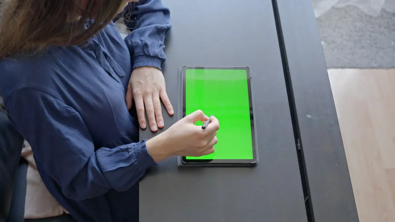 Female office worker drawing across green screen notepad