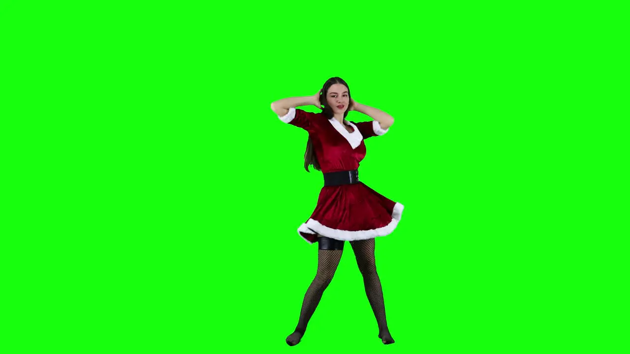 Sexy and seductive female dancer dancing in Christmas costume in front of a green screen