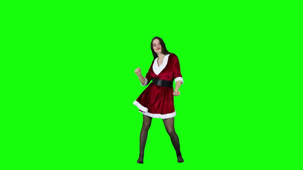 Happy and attractive female dancer in Christmas costume dancing in front of a green screen