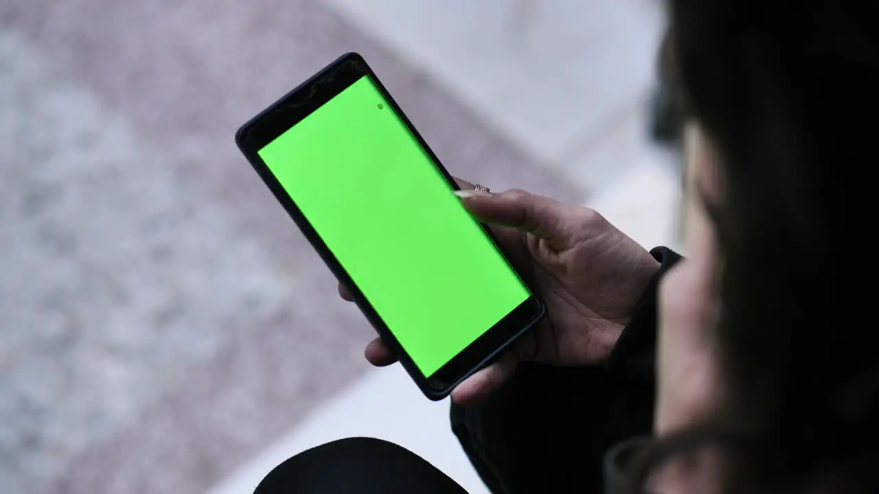 Over Left Shoulder Shot Of Hipster Pakistani Woman Holding A Green Screen Mobile