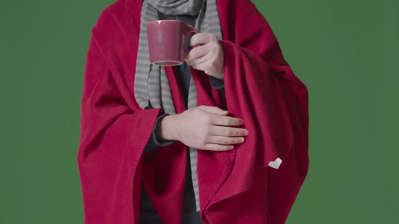 Close Up Of Person Wearing Blanket And Scarf With Hot Drink Trying To Keep Warm In Energy Crisis