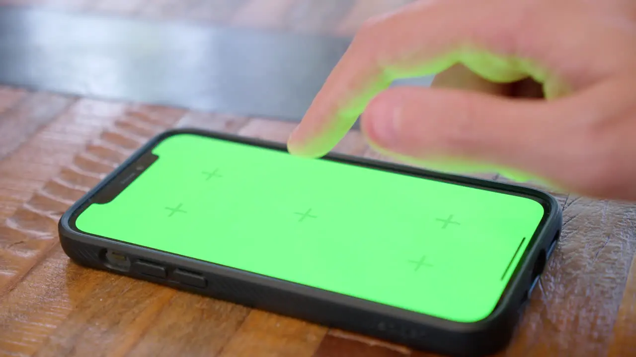 Iphone lying flat on a table screen displayed in close-up with green screen for replacement