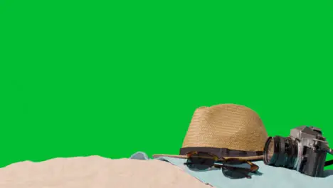 Summer Holiday Concept Of Sunglasses Sun Hat Camera Beach Towel On Sand Against Green Screen