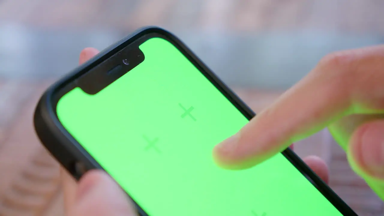 Close-up of top of iPhone screen being tapped and swiped with green screen for replacement