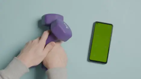 Overhead Fitness Studio Shot Of Male Hand Picking Up Exercise Dumbbell Weights Next To Green Screen Mobile Phone 6