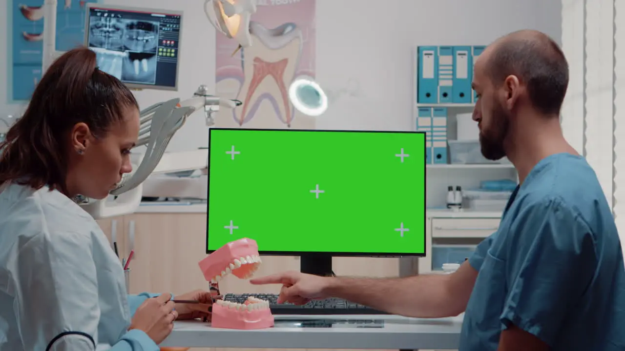 Oral care team looking at horizontal green screen on monitor