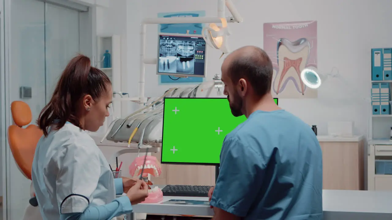 Woman dentist and man working with green screen on monitor