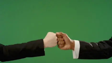 CU Colleagues in suits fist bump explosion on green screen