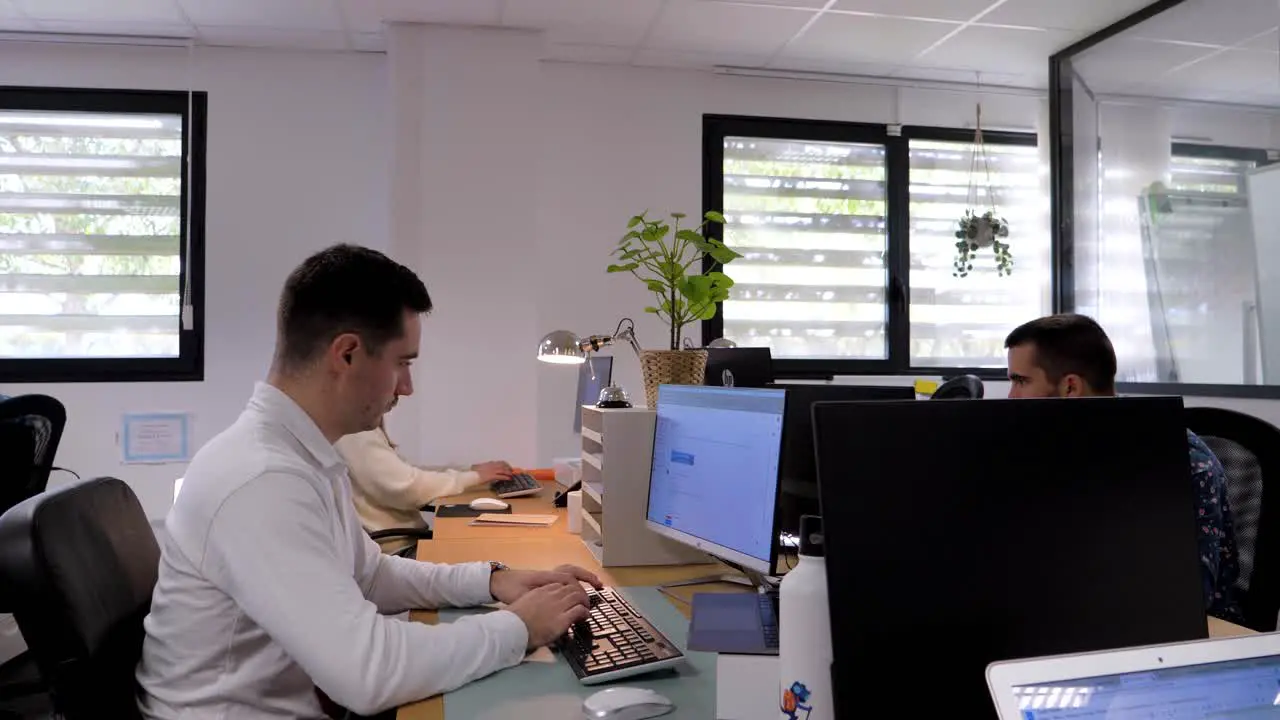 Slow motion dolly shot showing multiple colleagues working at their deks