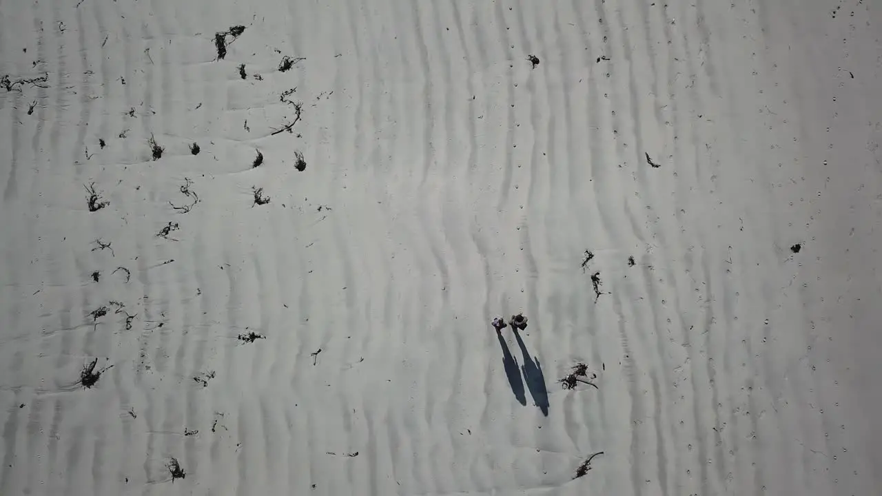 top aerial view of two people with their shadows walking on sand in Connemara Ireland