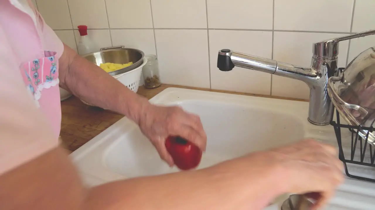 Senior lady cooking at home preparing paprika in the kitchen sink