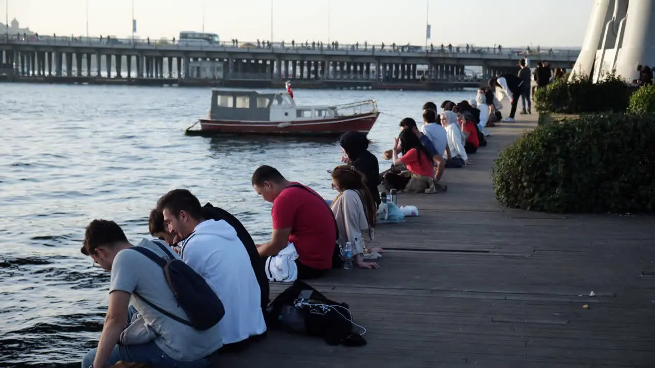 Young Turkish People are sitting in the coast of The Golden Horn Istanbul in a warm october day