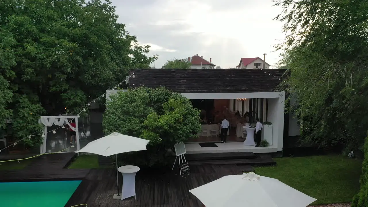 Zoom out drone shot of waiters serving at a pool party