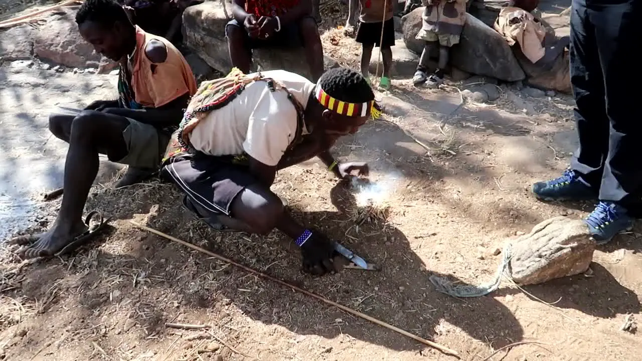 Tourists learning to make a fire with a Hadzabe tribe member in Tanzania Africa