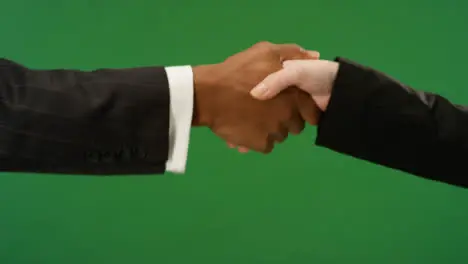 CU Two people in suits shaking hands on green screen