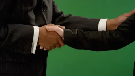 CU Man and woman shaking hands on green screen