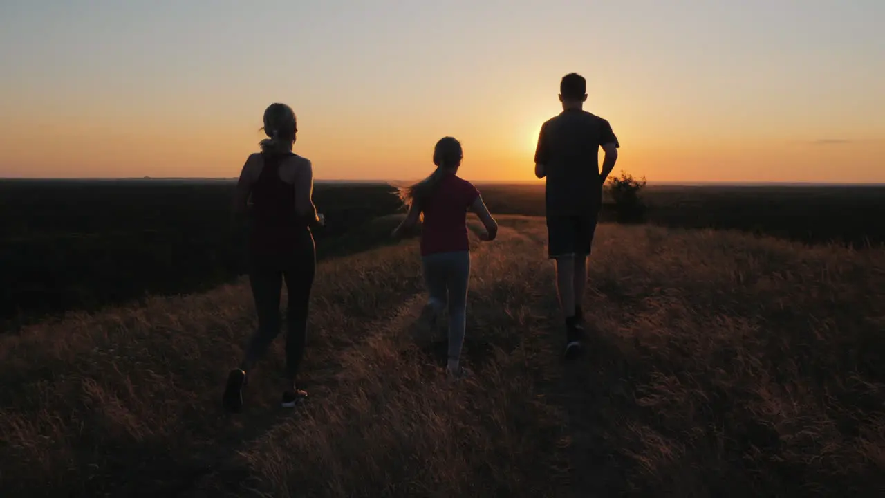 A Young Child With A Couple Jogging Outdoors In Scenic Location On The Sunset