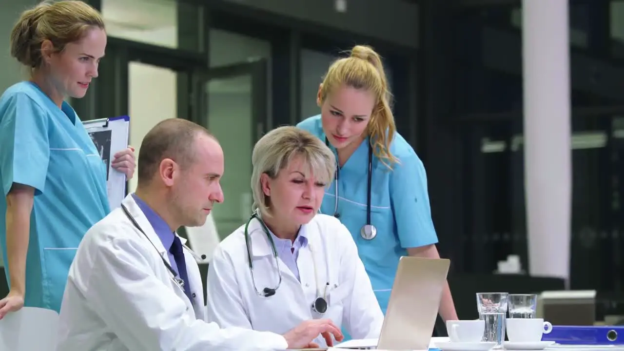 Doctors and nurse discussing over laptop in conference room