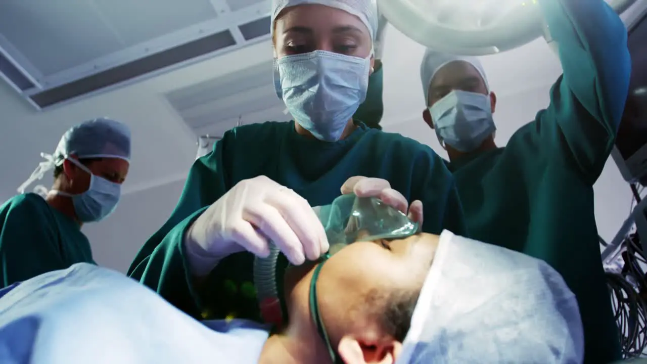 Surgeon putting oxygen mask on patient in operation room