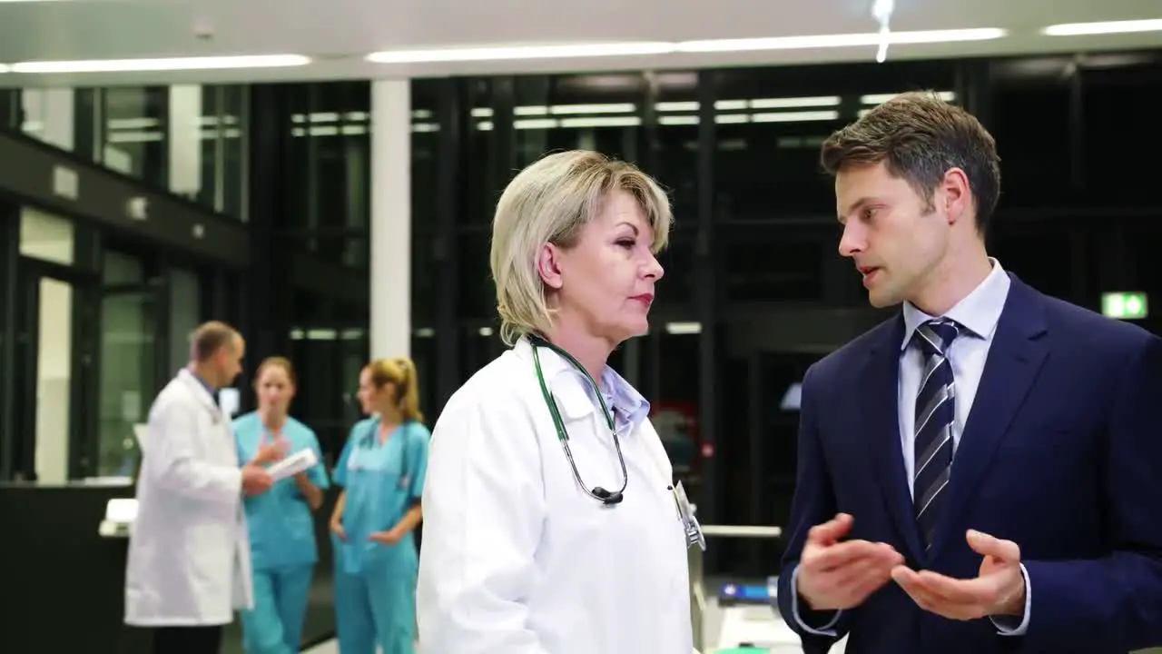 Female doctor interacting with businessman in corridor