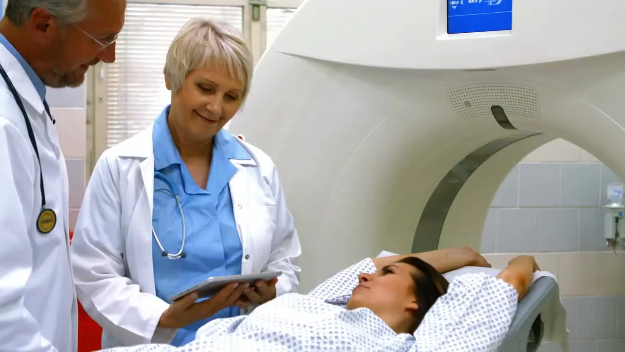 Doctors explaining diagnosis to female patient on digital tablet before mri scan