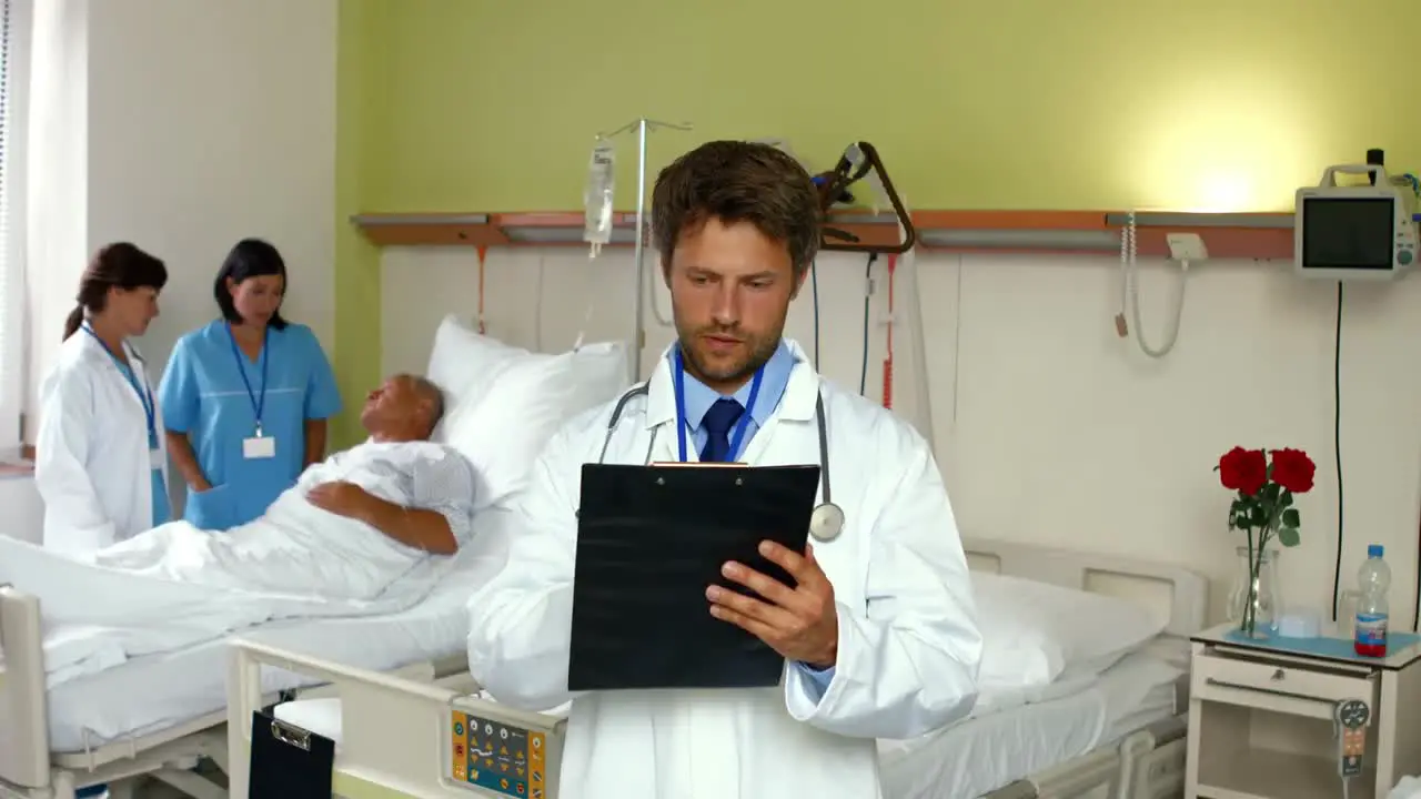 Doctor reading report while nurse interacting with patient in background