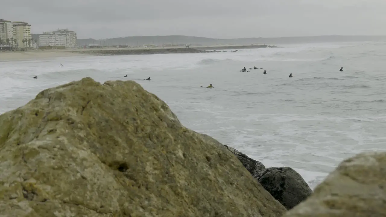 Group of surfers waiting for the best wave pov behind the rocks