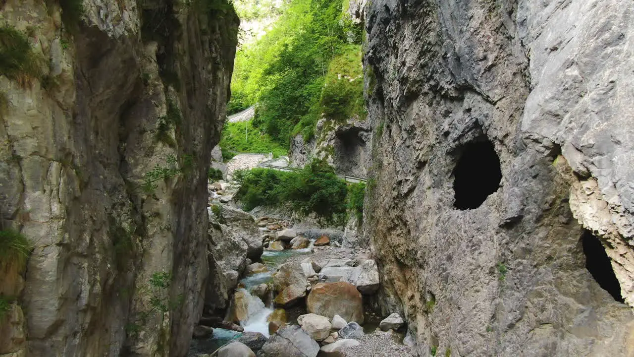 Shallow river flows between the rocks by the traffic road